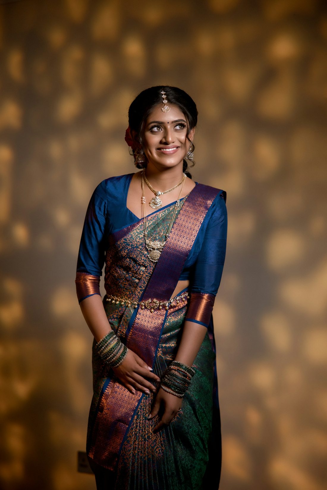 Woman in a navy blue silk saree with copper zari border, lit by warm festive lights